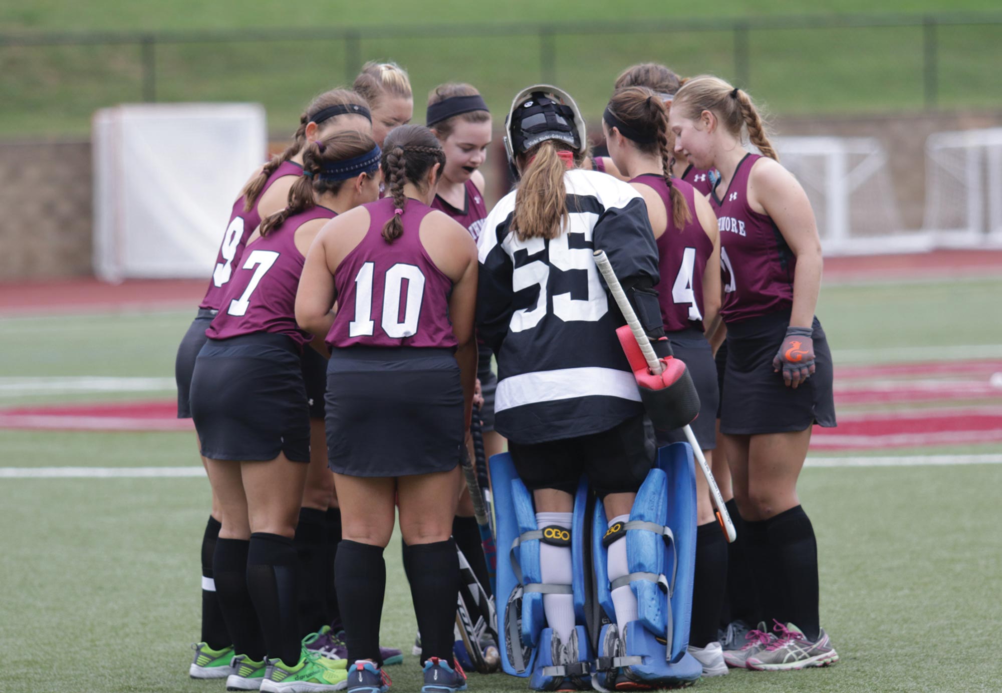 the women's field hockey team stands in a huddle