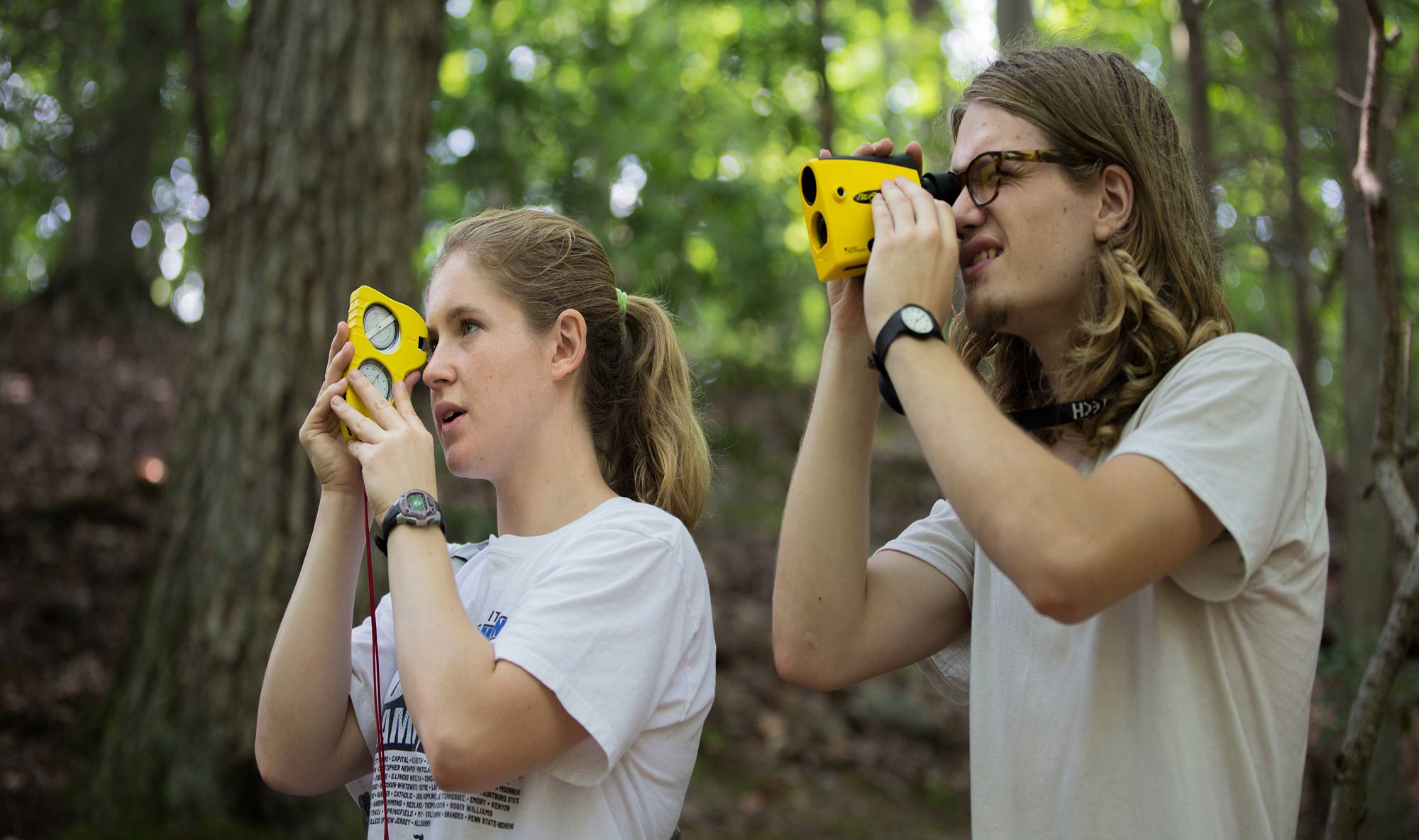 Two students use their binoculars to survey the landscape for their academic course