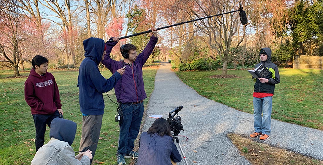 student film crew filming on a campus walkway