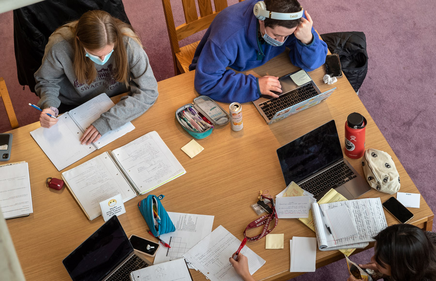 students sitting at a table doing homework in the library