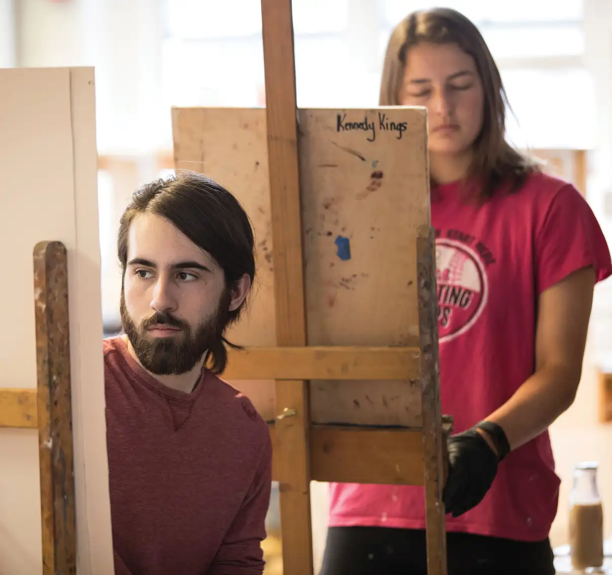 Two students drawing on easels