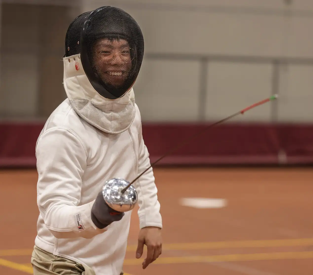 Student fencing and smiling
