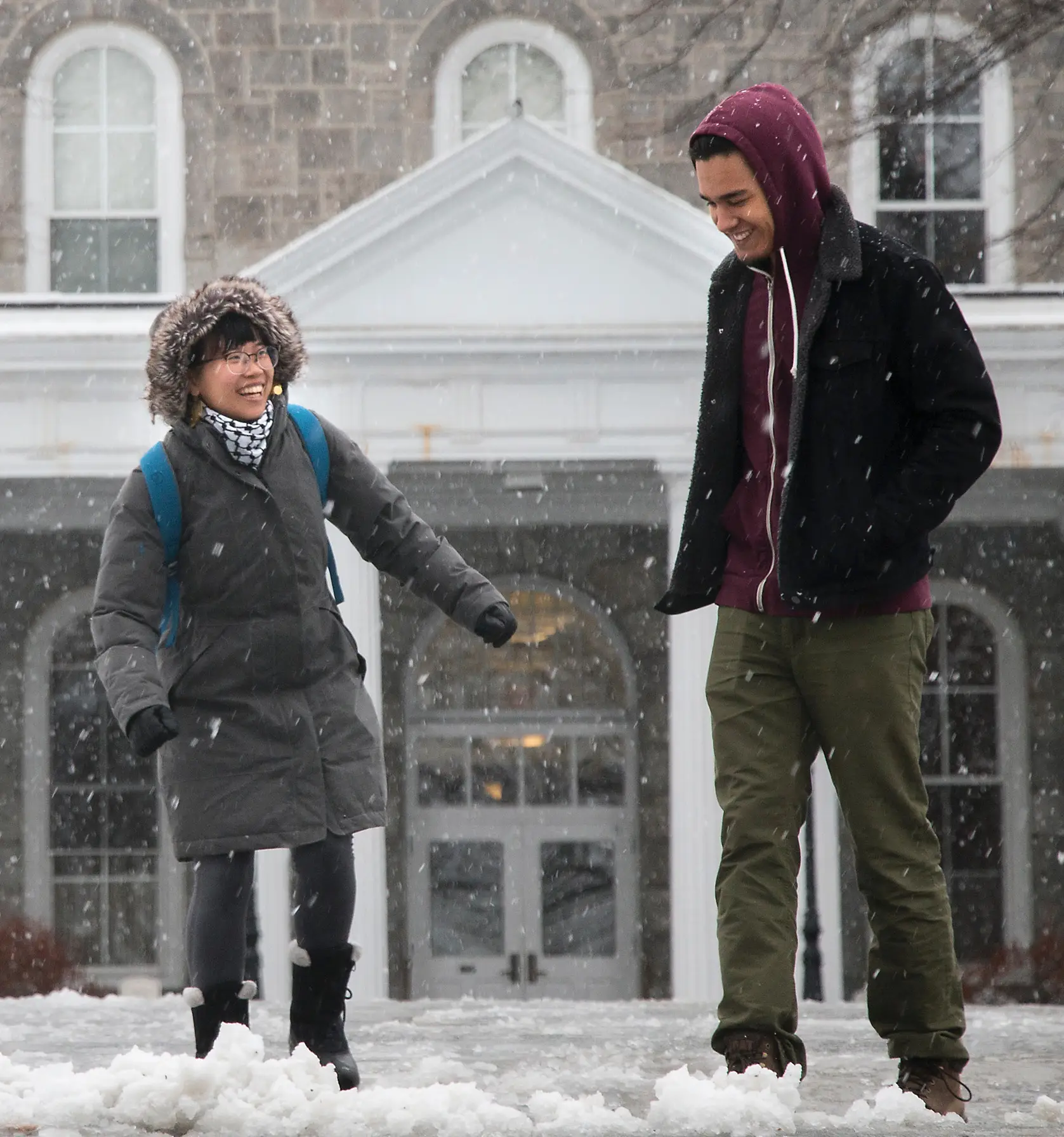 Two students smiling and laughing in snow