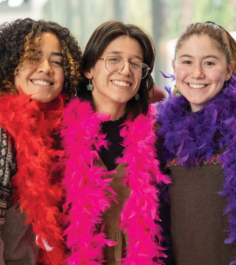 three female students weather bright colored scarves made of feathers