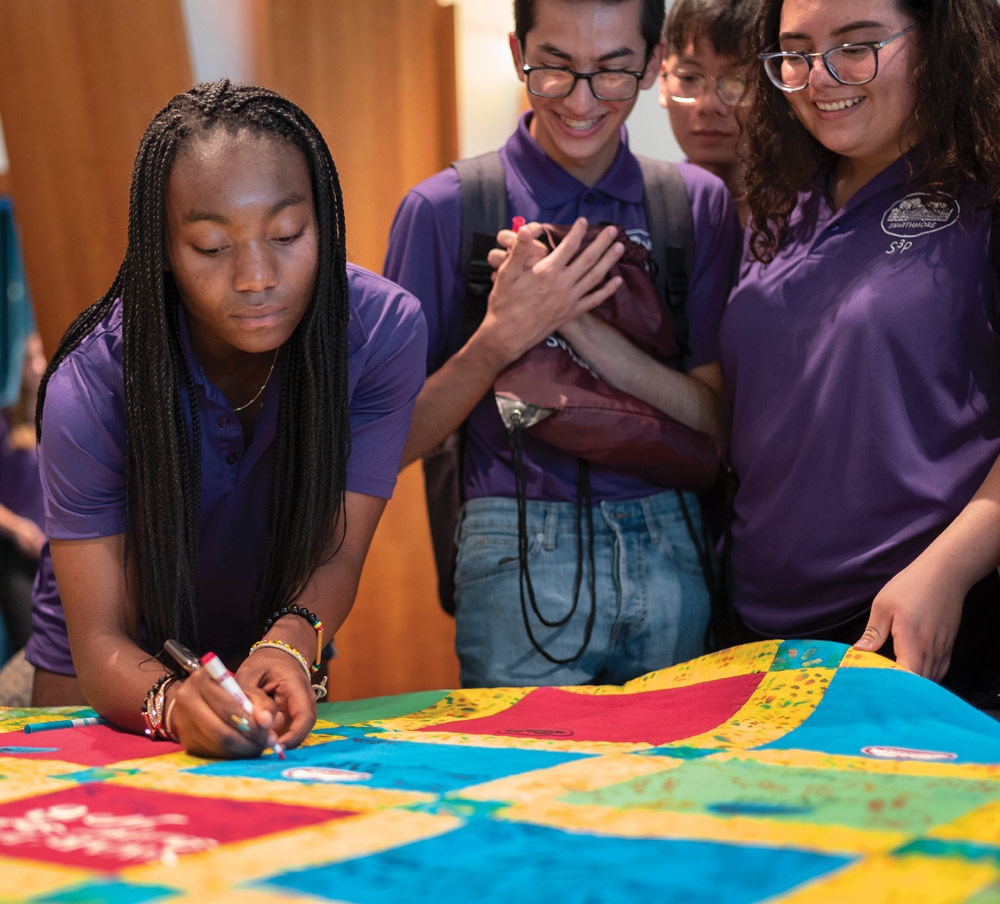 students signing a quilt
