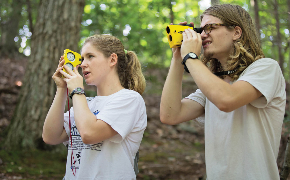 students using binoculars in the woods