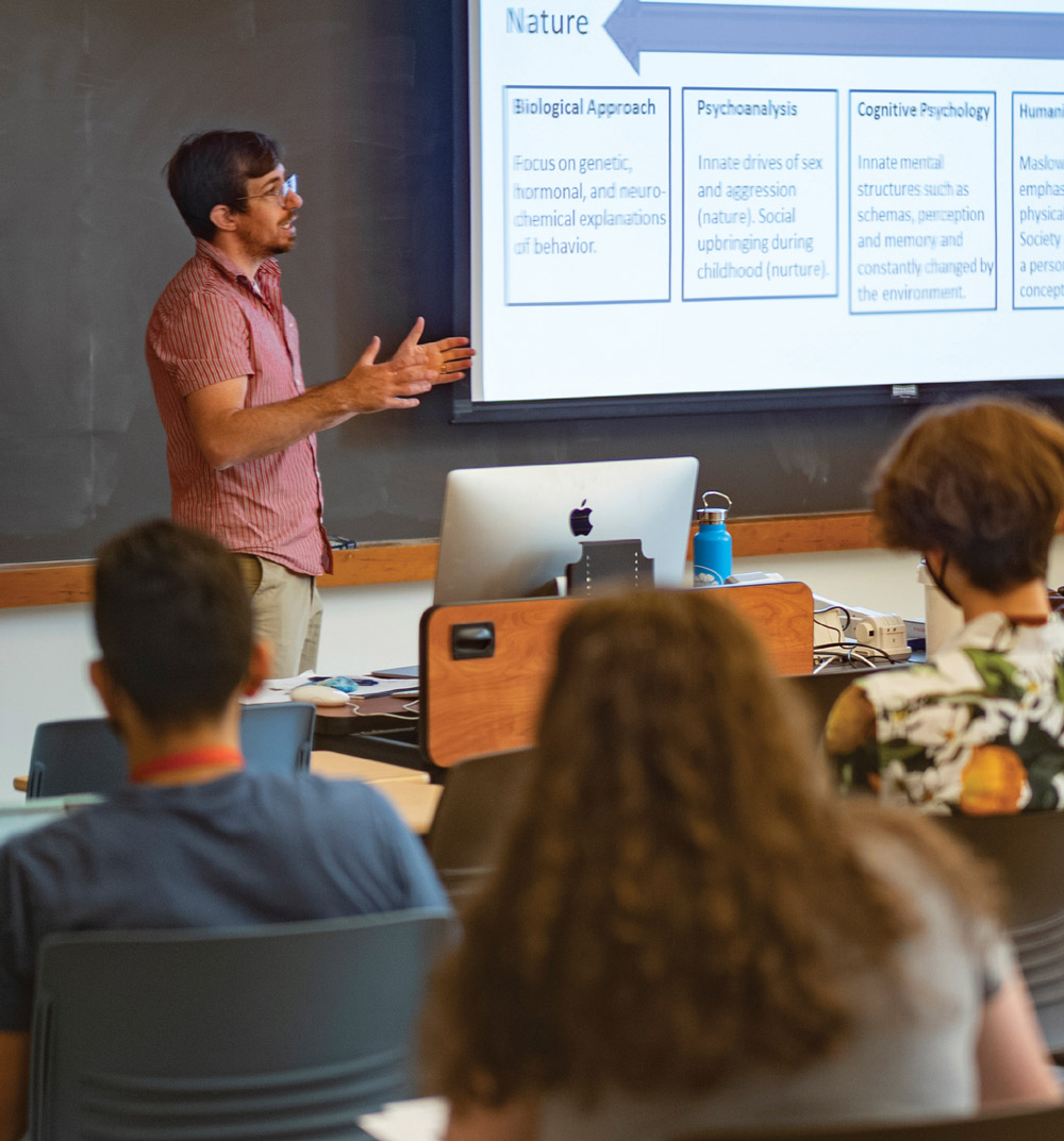teacher giving lecture in front of projector screen in classroom