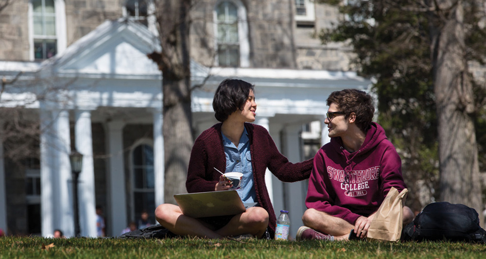 two Swarthmore students sitting on the grass while doing work