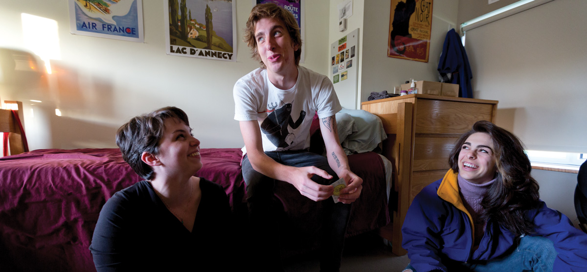 three students hanging out in a dorm room