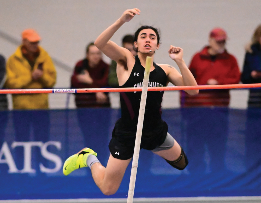 Athlete jumping over a pole in a high jump event indoors.
