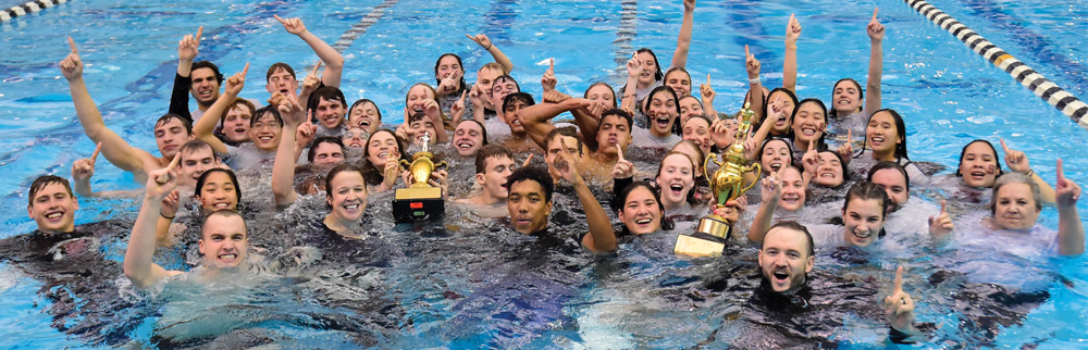 A group of people celebrating with trophies in a swimming pool.
